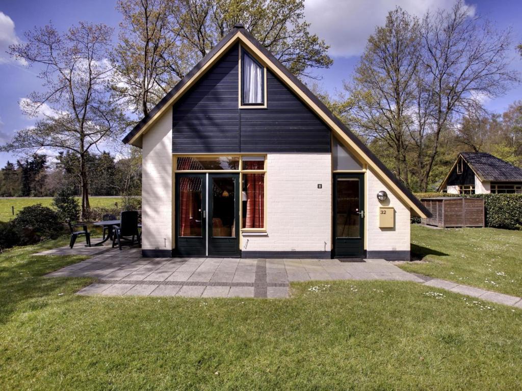 a small black and white house with a patio at Holiday Home Buitenplaats Gerner-7 by Interhome in Dalfsen