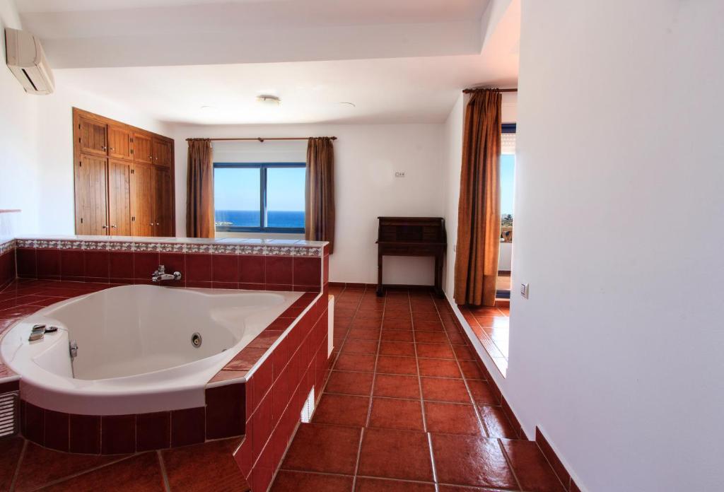a large bathroom with a tub with a view of the ocean at Hostal El Dorado in San José