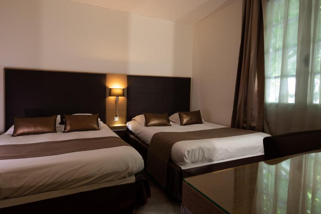 a hotel room with two beds and a window at Hotel Restaurant du Centre et du Lauragais in Castelnaudary