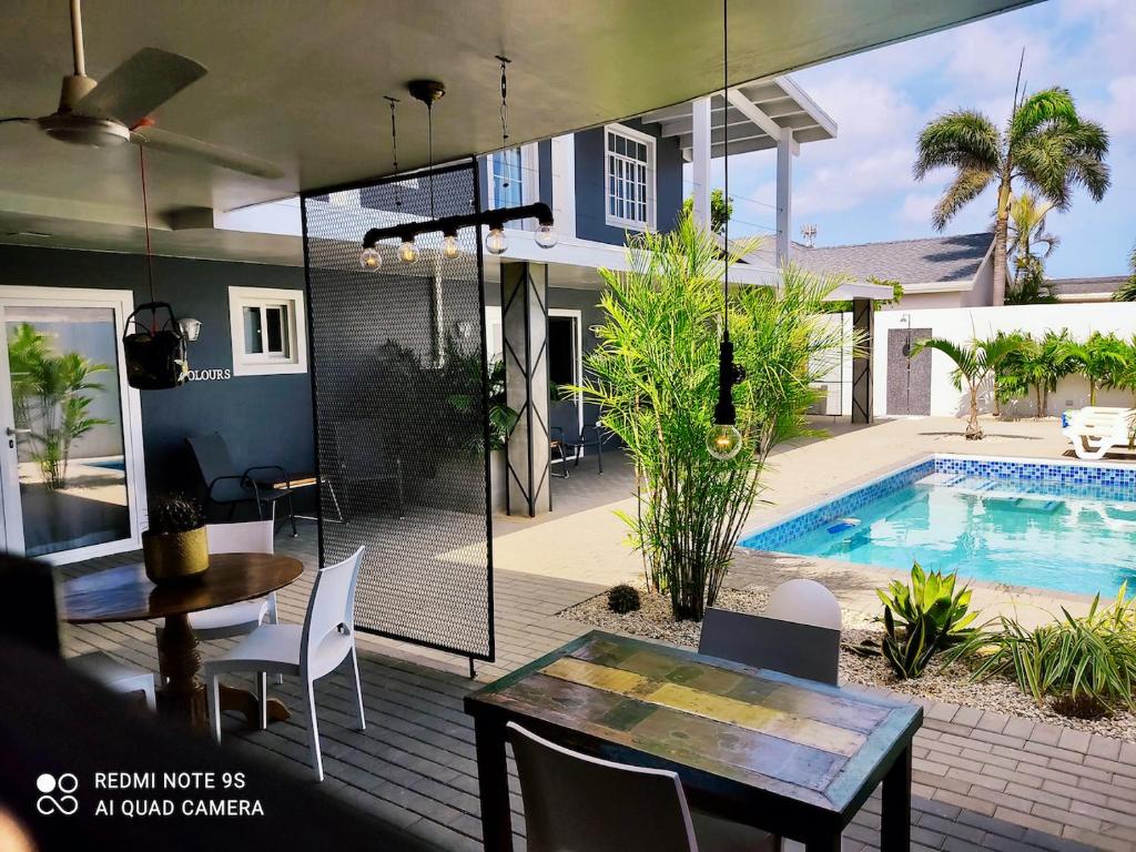 eine Terrasse mit einem Tisch und Stühlen sowie einem Pool in der Unterkunft Studios 11and11Aruba in Palm-Eagle Beach