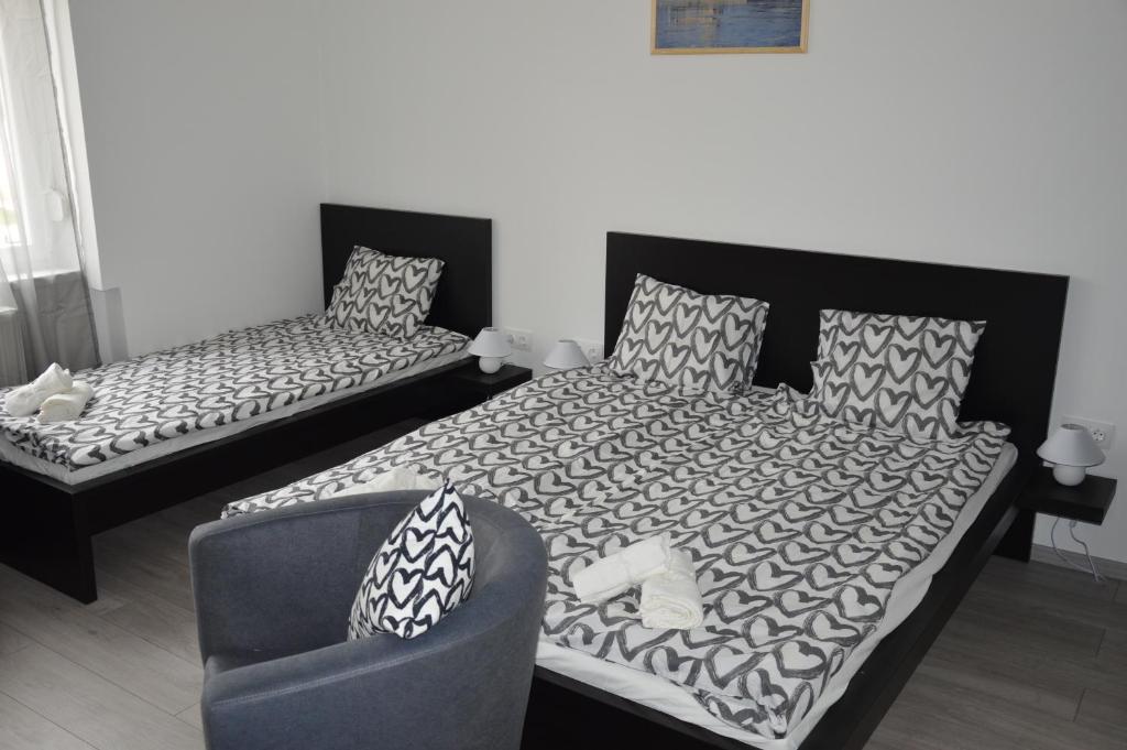 a bedroom with two beds and a chair at Apartman-Tata in Tata