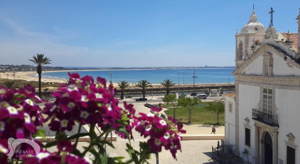 um edifício com flores cor-de-rosa em frente a uma praia em Infante Guesthouse em Lagos