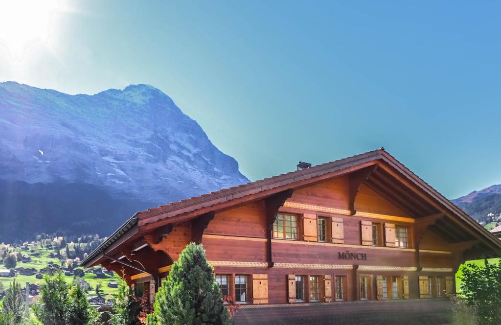 ein großes Holzgebäude mit einem Berg im Hintergrund in der Unterkunft Excellent flat with a fantastic view of the Eiger! in Grindelwald