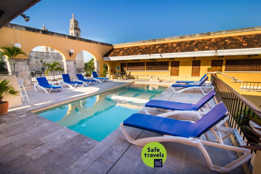 einen Pool mit Liegestühlen neben einem Gebäude in der Unterkunft Hotel Caribe Merida Yucatan in Mérida