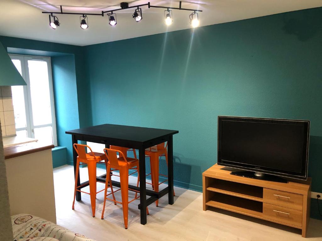 a dining room with a table and two chairs and a television at Appartement porte du cantal in Massiac