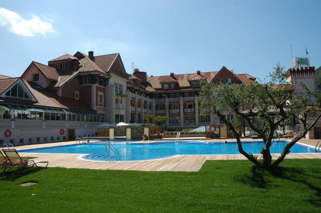 un grand bâtiment avec une grande piscine dans une cour dans l'établissement Gran Hotel Balneario De Puente Viesgo, à Puente Viesgo