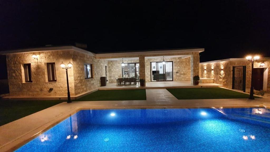 a swimming pool in front of a house at night at Villa Yermanina in Yeroskipou