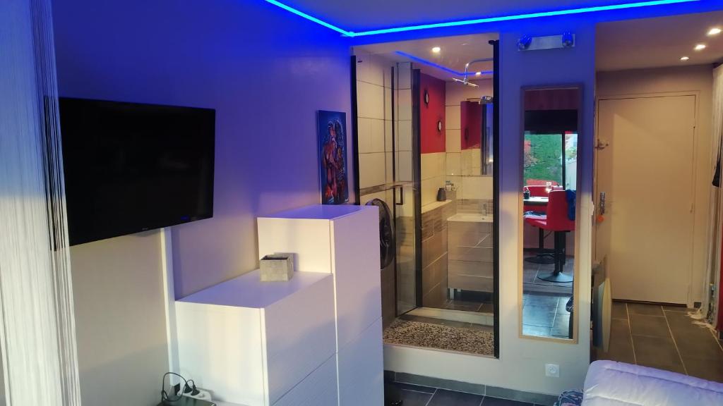 - un salon avec une télévision et un mur violet dans l'établissement Le Vénusia du CAP - Clim, stationnement, ménage et linge fournis, au Cap d'Agde