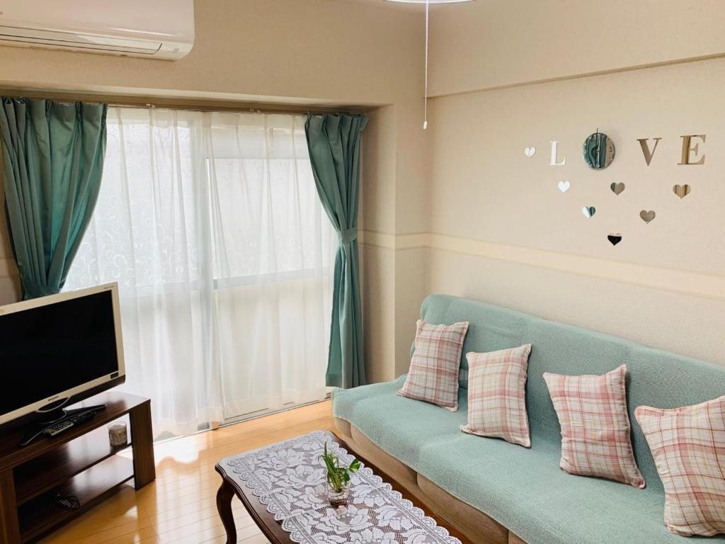 K&M Heights - Vacation STAY 32220v في طوكيو: غرفة معيشة مع أريكة زرقاء وتلفزيون