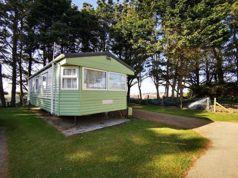 una pequeña casa verde sentada en el césped en Newquay Caravan Holiday, en Newquay