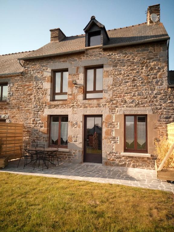 une maison en pierre avec des tables de pique-nique devant elle dans l'établissement Gite de charme Les Buissonnets, à Plesder