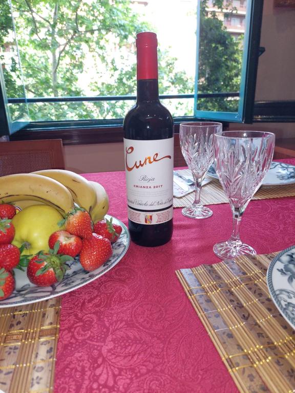 a bottle of wine sitting on a table with a plate of fruit at Apartamento Gran Via de les Corts Catalanes in Barcelona