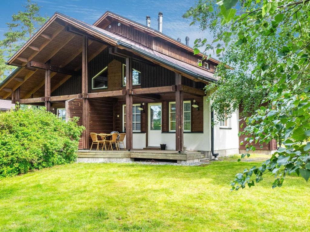 une maison en bois avec une terrasse couverte et une pelouse dans l'établissement Holiday Home Tahkon klubitie 2 a by Interhome, à Tahkovuori