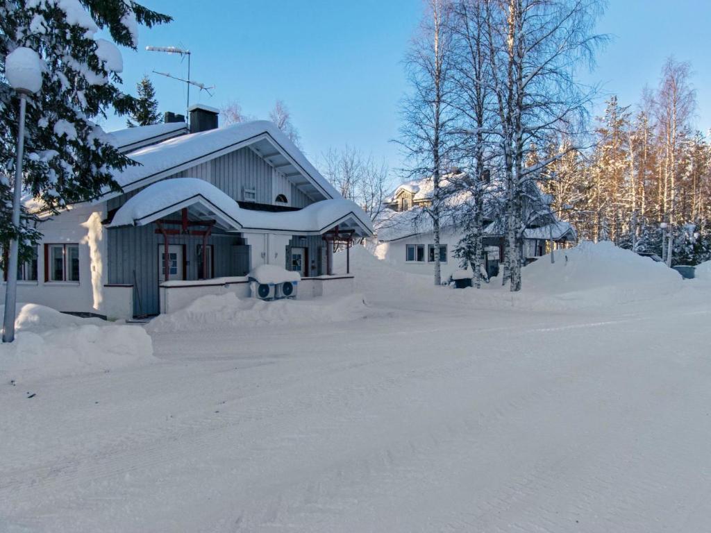 une maison recouverte de neige dans une cour dans l'établissement Holiday Home Hallantytär a1 paritalo by Interhome, à Hyrynsalmi