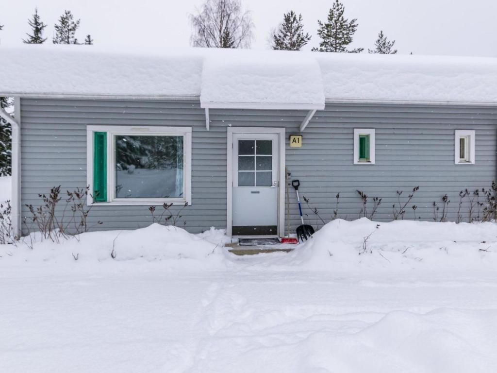 a gray house with a white door in the snow at Holiday Home Kotipaljakka a1 by Interhome in Kotila
