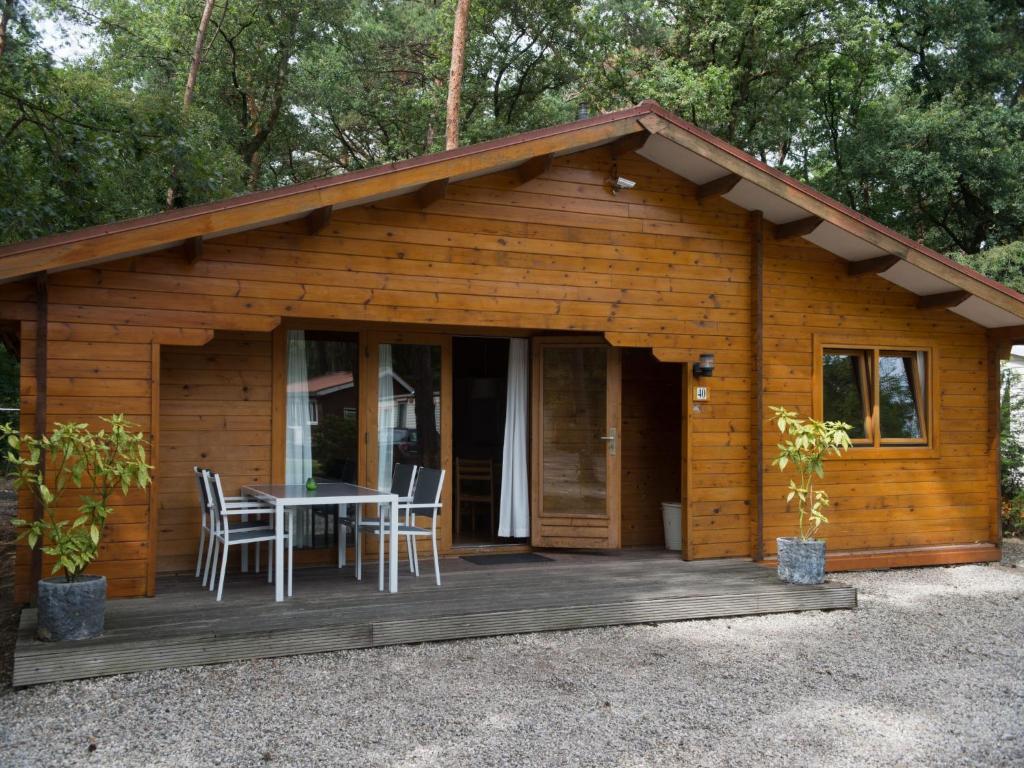 eine Hütte mit einem Tisch und Stühlen auf einer Terrasse in der Unterkunft Holiday Home De Brenkberg in Schinveld