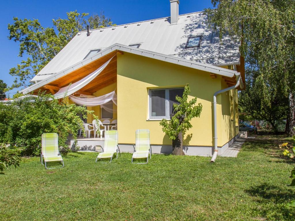 a yellow house with chairs in the yard at Holiday Home Francois by Interhome in Balatonberény