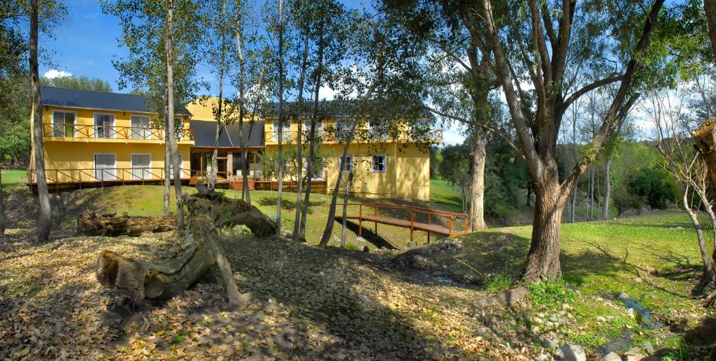 a large yellow house in the middle of trees at Posada Quellen in Villa General Belgrano