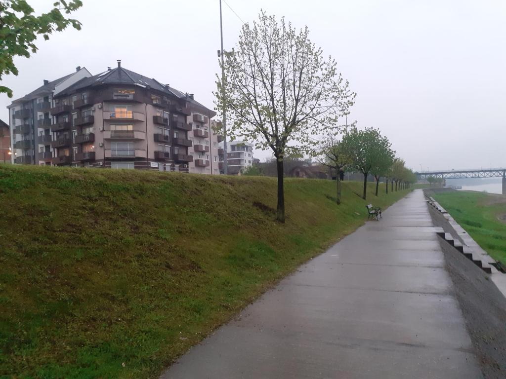 einen Fußweg in einem Park mit einem Gebäude im Hintergrund in der Unterkunft Apartment Setaliste in Brčko