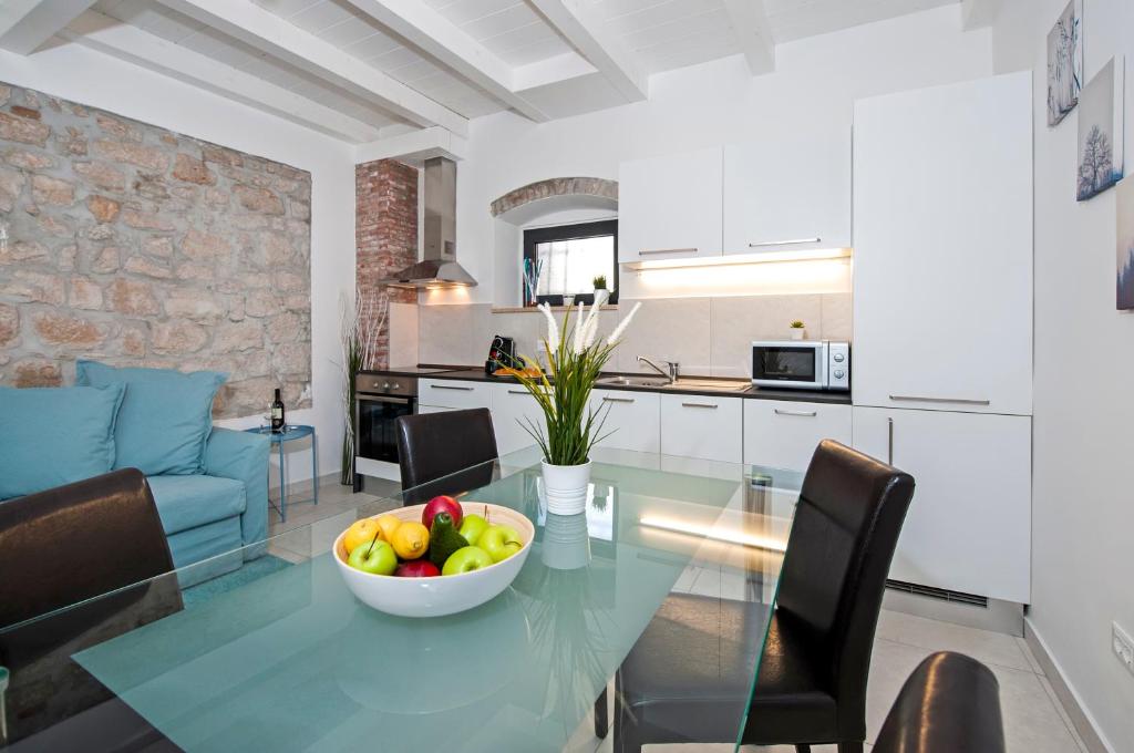 eine Küche und ein Wohnzimmer mit einem Glastisch mit einer Obstschale in der Unterkunft Marcus home in Rovinj