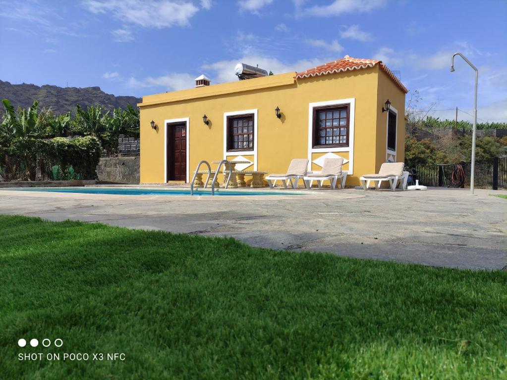 una casa amarilla con un patio de juegos delante de ella en Casa Pedro en Tazacorte