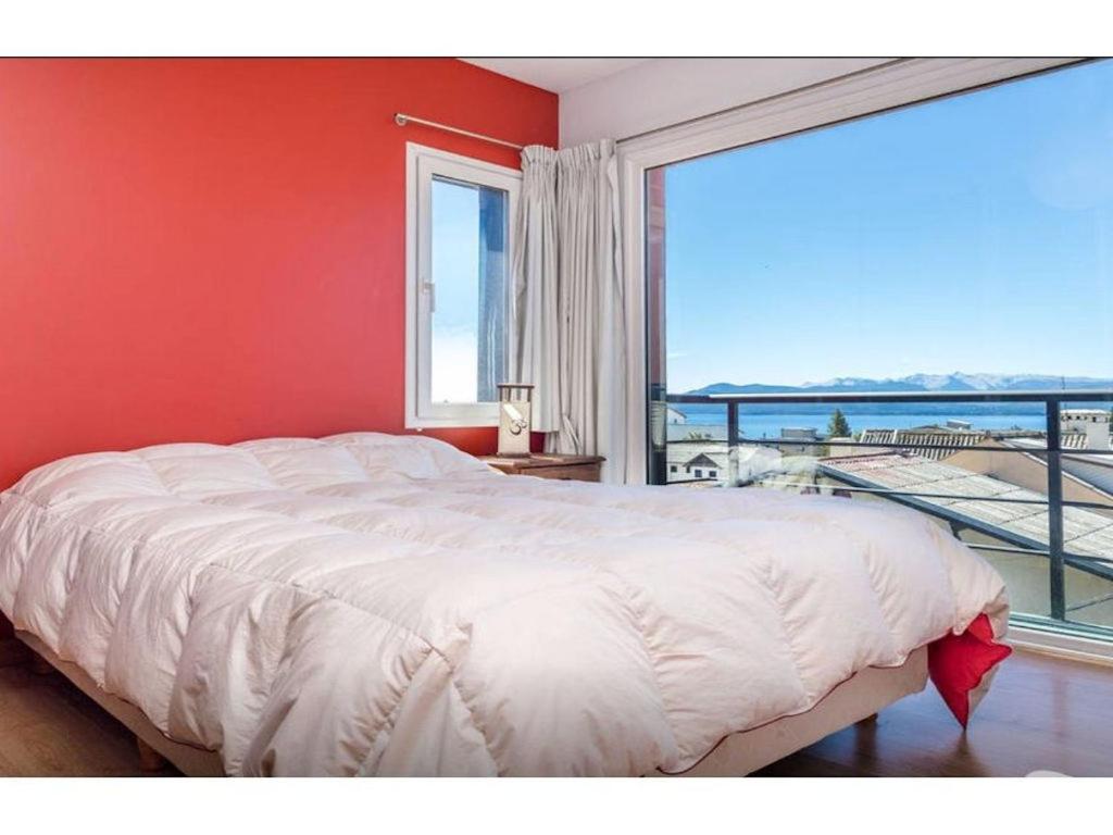 ein Schlafzimmer mit einem großen Bett und einem großen Fenster in der Unterkunft MODERNO DEPARTAMENTO CON VISTA AL LAGO in San Carlos de Bariloche