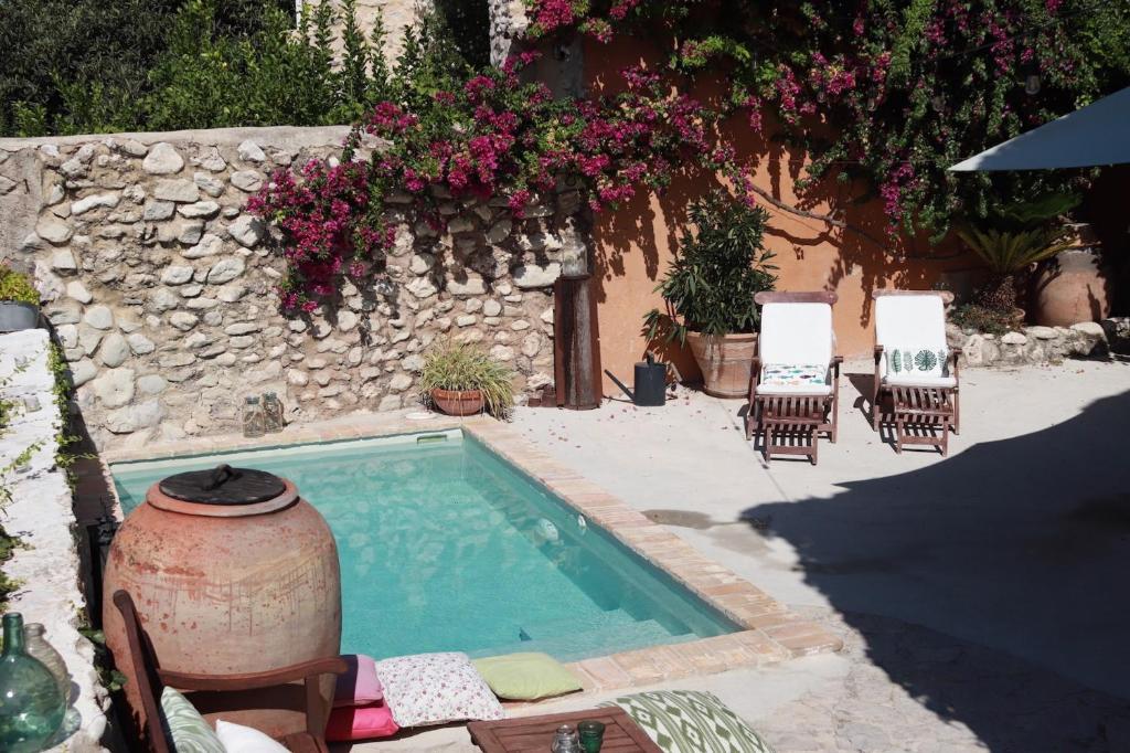 a swimming pool with chairs and a wall with flowers at Ca la Pasita 26 in Beniali