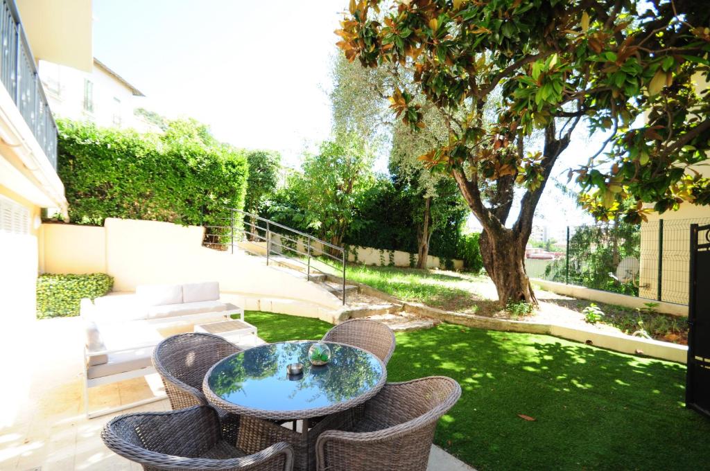 eine Terrasse mit einem Tisch und Stühlen im Hof in der Unterkunft Les Volets Bleus in Nizza