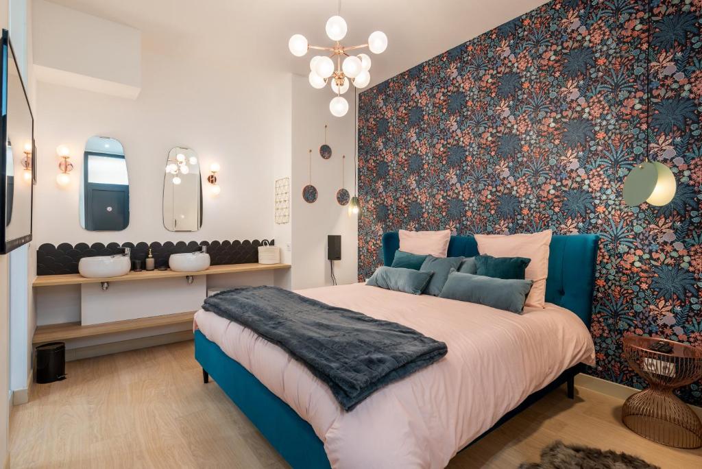 Un dormitorio con una cama azul con una pared de acento floral en Le Cocon Hygge & SPA en Lyon