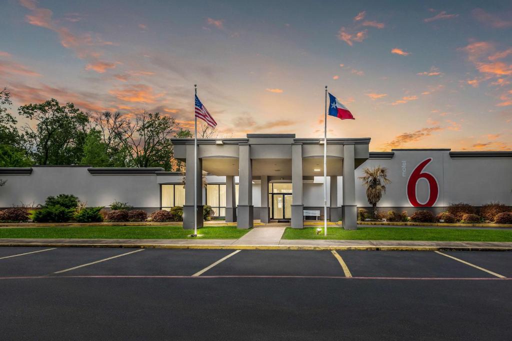 a building with two flags in a parking lot at Motel 6-Henderson, TX in Henderson