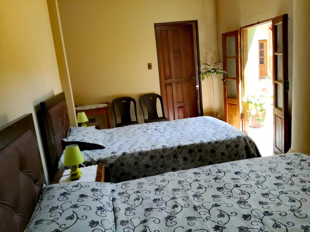 a bedroom with two beds and a table with chairs at ALSIGAL COCHABAMBA Casa de Huéspedes in Cochabamba