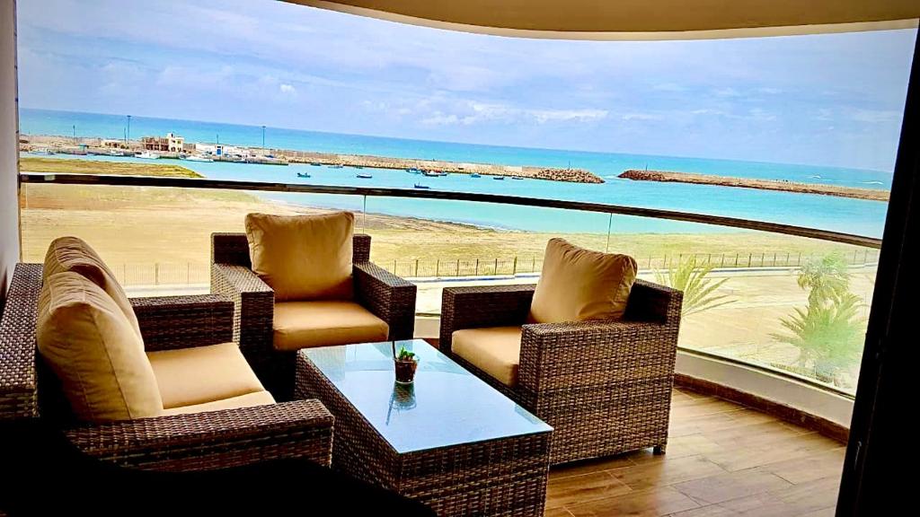 a balcony with chairs and a table and a view of the beach at RESIDENCE PUERTO MARINA Corniche d'Asilah in Asilah
