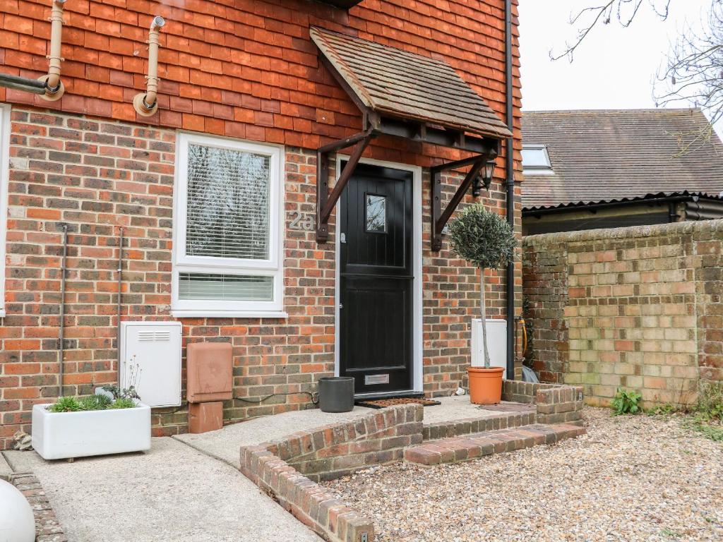 ein Backsteinhaus mit einer schwarzen Tür und einem Fenster in der Unterkunft 2A The Mews in Havant