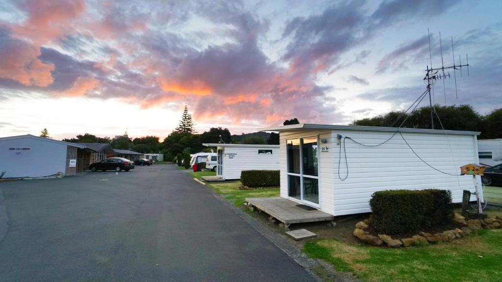 a house with a parking lot with a cloudy sky at Whangarei Central Holiday Park in Whangarei