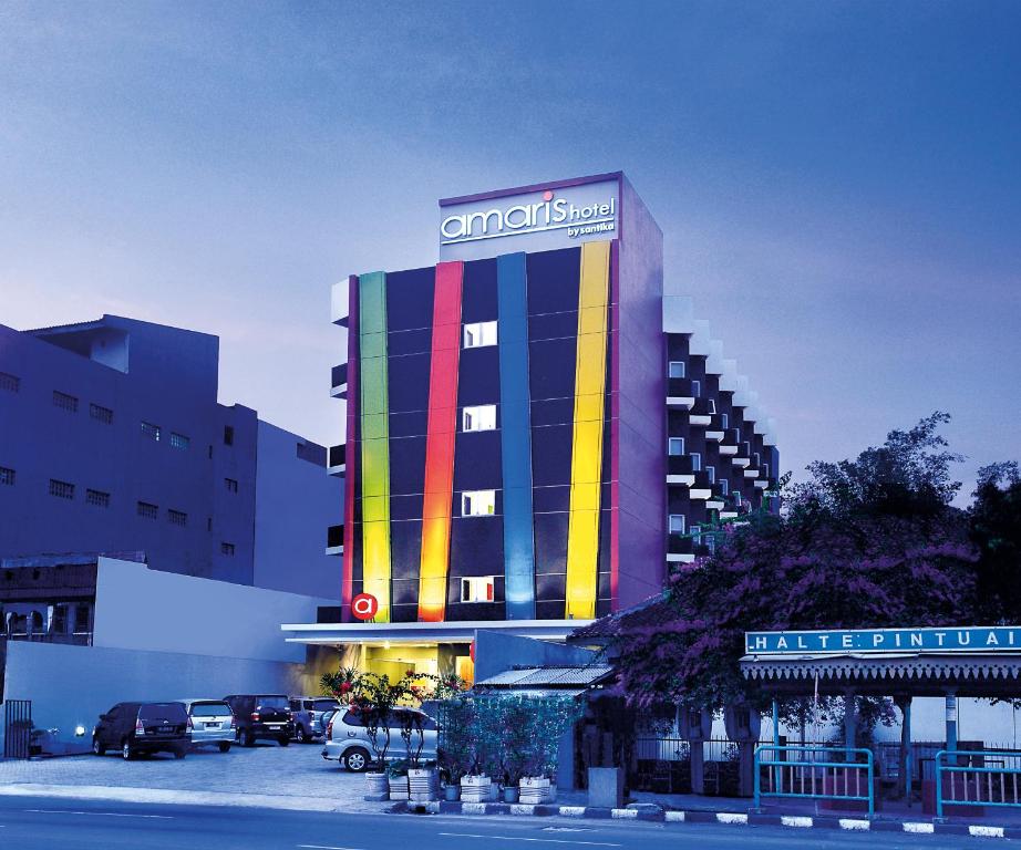 a building with a colorful facade with cars parked in a parking lot at Amaris Hotel Juanda in Jakarta