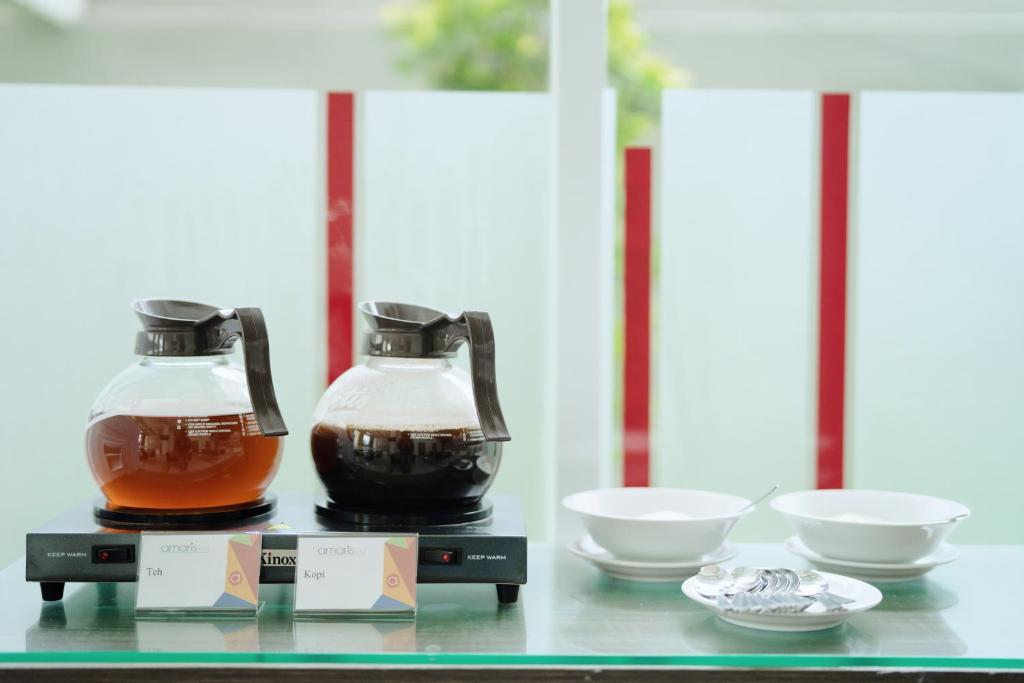 two bottles of honey and bowls on a glass table at Amaris Hotel Juanda in Jakarta