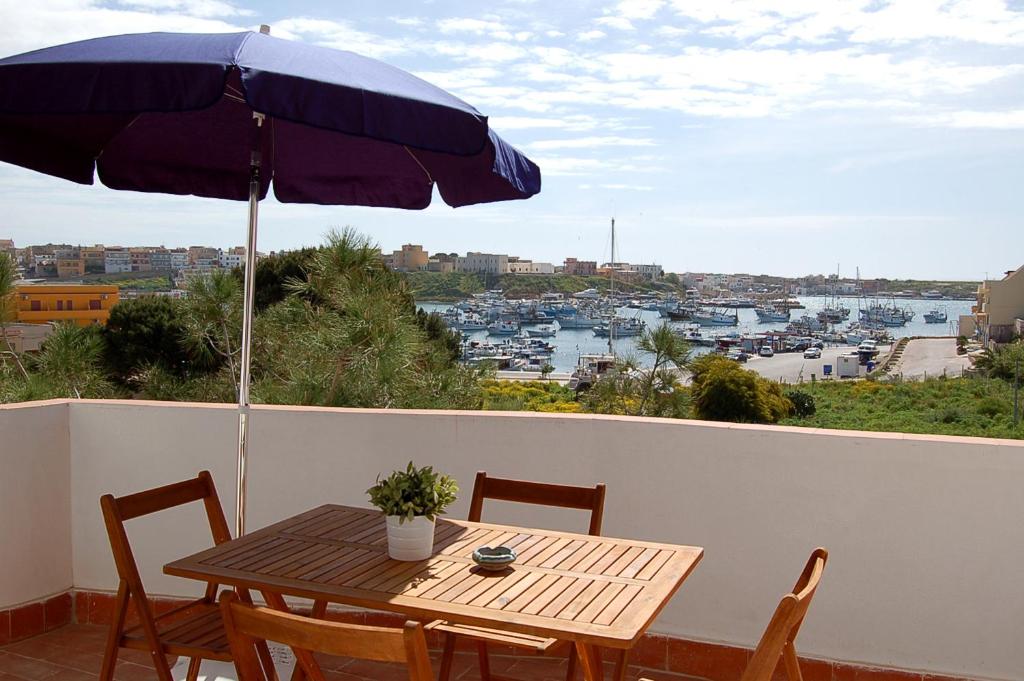 einen Tisch und Stühle mit Sonnenschirm auf dem Balkon in der Unterkunft Case Vacanze Farchikalà in Lampedusa