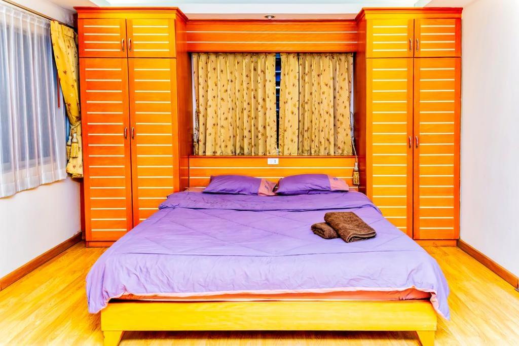 1 dormitorio con 1 cama con puertas amarillas y sábanas moradas en JOLLY GUESTHOUSE & RESTAURANT, en Pattaya central