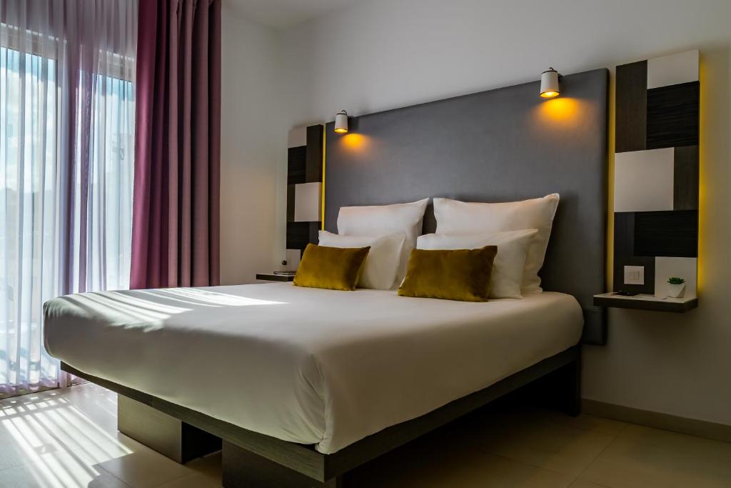 a bedroom with a large bed with yellow pillows at Hotel Valentina in St. Julianʼs
