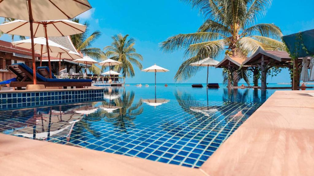 a swimming pool with umbrellas and the ocean at Sasitara Thai Villas in Choeng Mon Beach