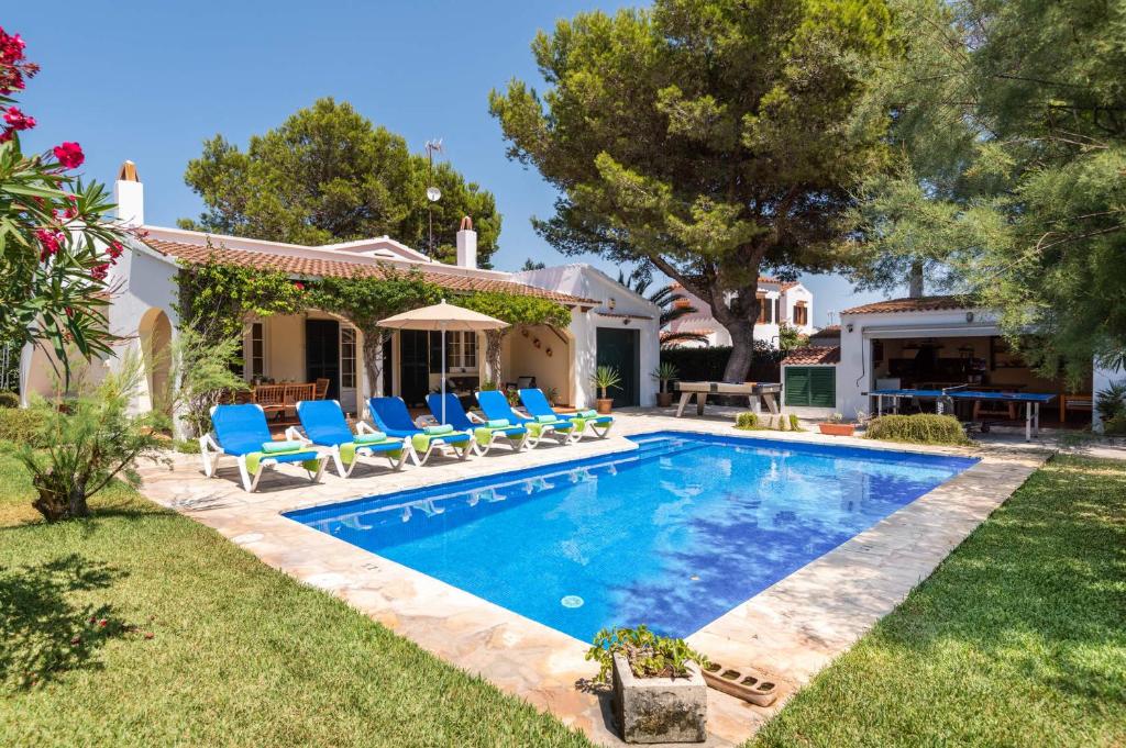 a swimming pool with chairs and a house at Villa Siena by Villa Plus in Cala en Blanes