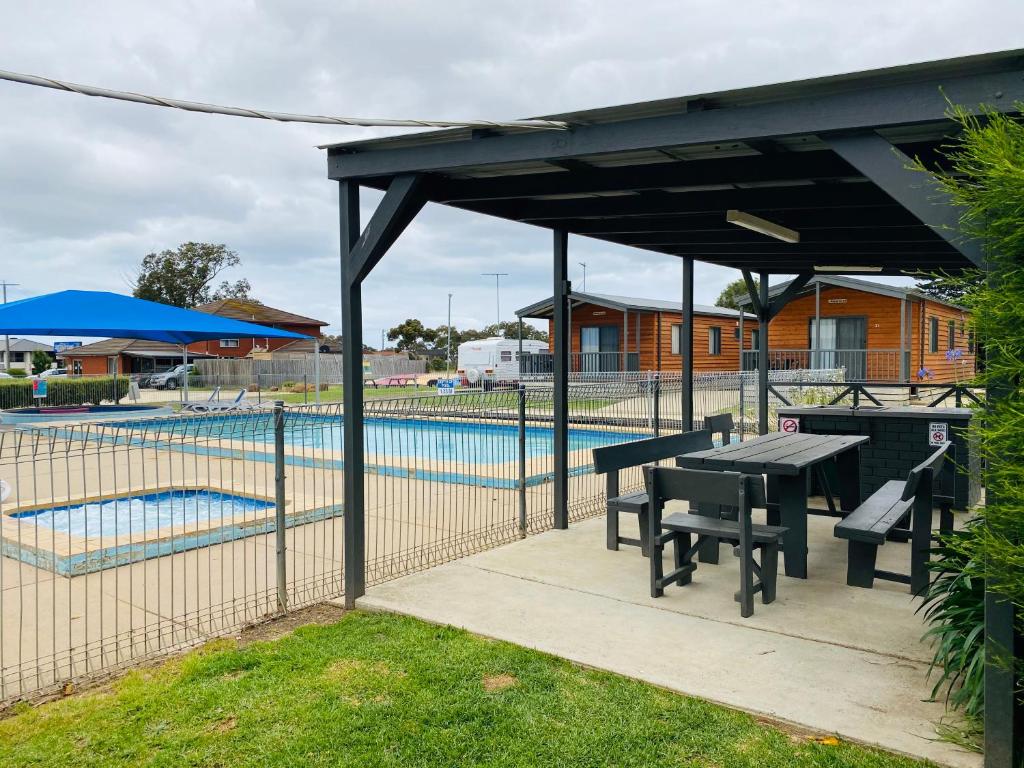 un pabellón con mesa y bancos junto a una piscina en Geelong Surfcoast Hwy Holiday Park, en Mount Duneed