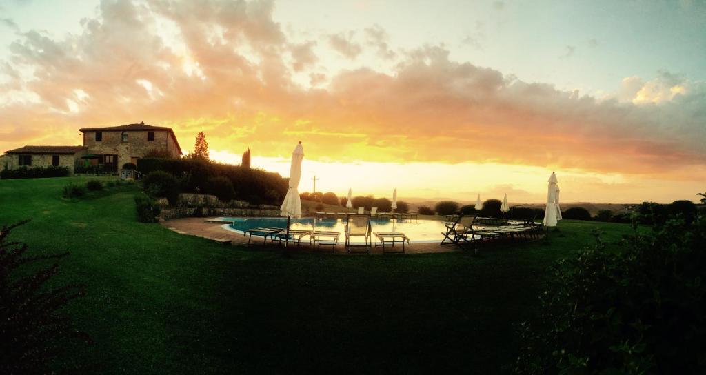 un gruppo di tavoli e ombrelloni di fronte a una casa di Agriturismo Fattoria Di Corsano a Corsano