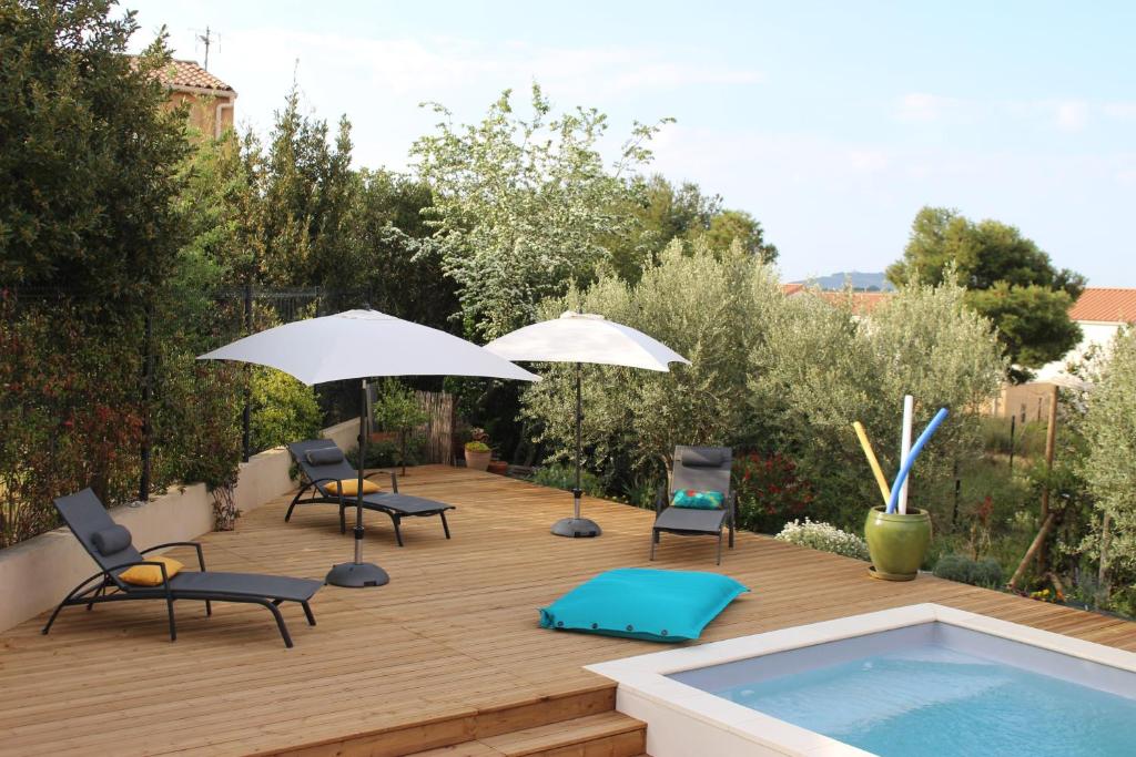 une terrasse avec des chaises et des parasols, ainsi qu'une piscine dans l'établissement Le Terracotta , 2chambres, Terrasse, Piscine, Parking gratuit, Wifi, Climatisation, à Marseillan