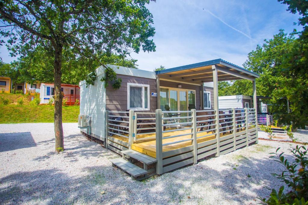 a tiny house with a porch and a tree at CHERRY Premium JADE Mobile homes Zelena Laguna in Poreč