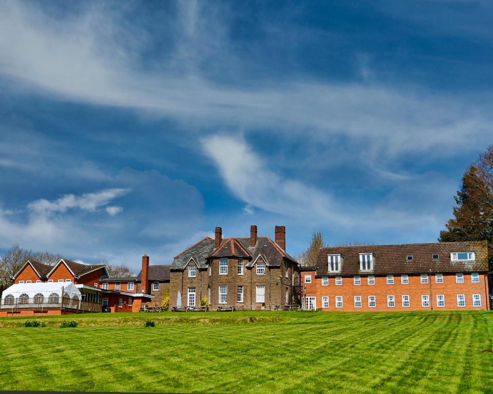 ein großes Backsteingebäude mit einem Grasfeld davor in der Unterkunft Pilgrim Hotel in Hereford