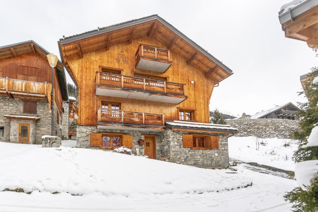 a large wooden building with a balcony in the snow at La Grange de Marie in Les Allues