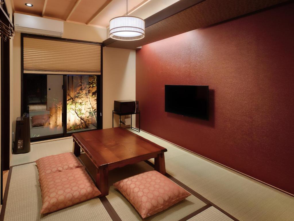 a living room with a table and a tv on a wall at Kanade Fushimiinari-Inometei in Kyoto