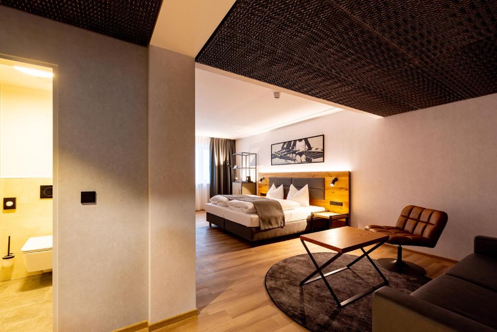 mk hotel passau في باساو: غرفة نوم مع سرير وغرفة معيشة