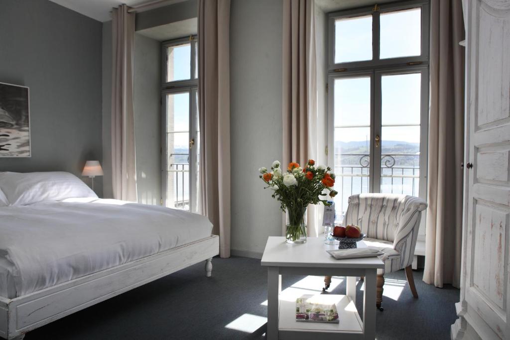 a bedroom with a bed and a table with a vase of flowers at Hotel Hirschen am See in Meilen